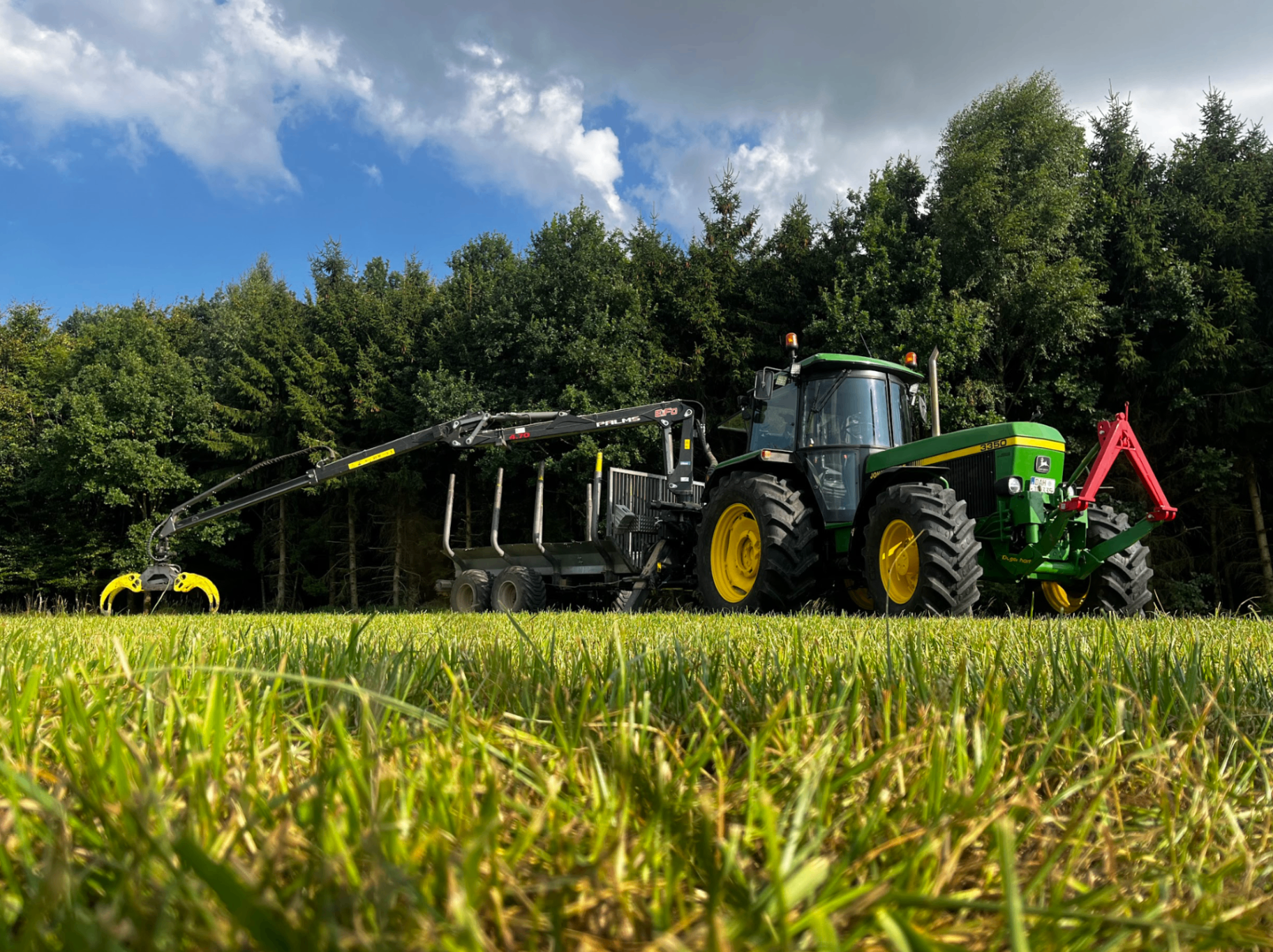 Forstarbeiten bei Sonnenuntergang – Traktor mit Holzstämmen